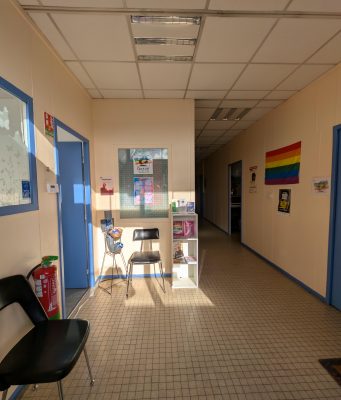 Permanences d’accueil : nouveaux horaires ! Couloir d’accueil du local de QUAZAR à Angers, avec affiches LGBTQIA+, espace d’attente et portes des bureaux des permanences